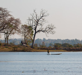 Fisherman on canoe in tropical Bungva lake, Laos