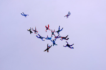 A group of skydivers is falling in the cloud.