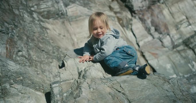 Little toddler climbing to top of rock