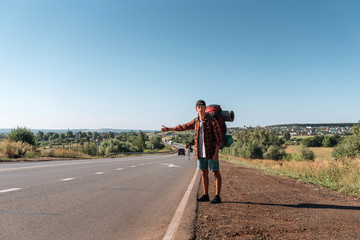 Fototapeta premium Travel man hitchhiking. Backpacker on road