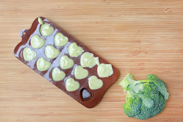 Container for freezing with baby food on wooden board. Top view.