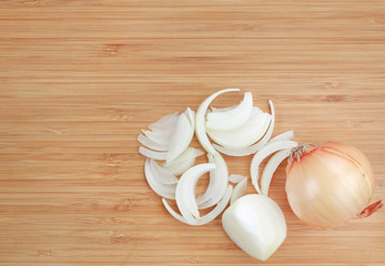Sliced onions on wooden cutting board close up. Top view.
