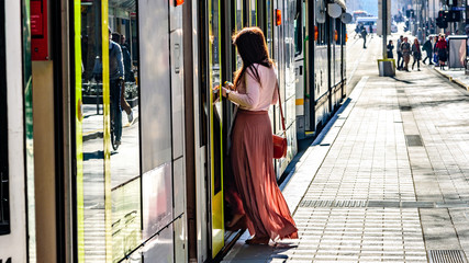An unidentified female with a long dress is getting onboard a Melbourne Australia city tram in the...