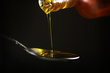 Oil pouring to the spoon from the bottle