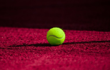 A lonely Tennis Ball on a Sand Court