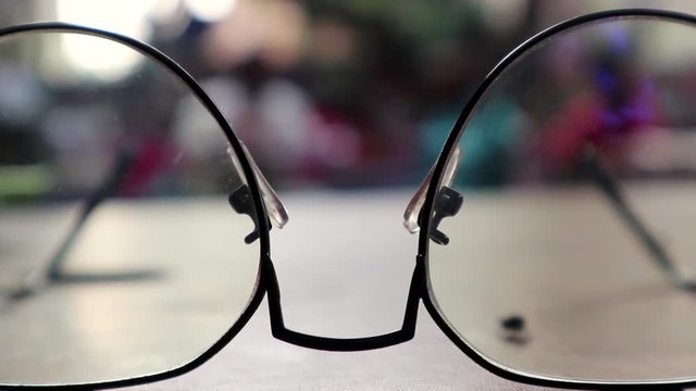 eye glass on coffee table with people on background (asia) with fly