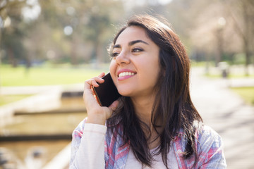 Smiling delighted girl enjoying nice phone talk outdoors