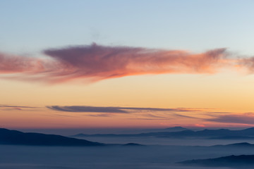 Beautifully colored sky at dusk, with mountains layers and mist between them