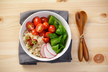 Quinoa salad with vegetables, raspberry and tomatoes on the wooden table. Super food for healthy and concept of balanced diet