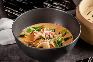 Pan-Asian cuisine concept. Japanese miso soup Tom Yam Kung with seafood, shrimps, mussels, calamari. Serving dishes in the restaurant in the bowl. Background image.