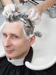 A man washes his hair after a haircut.