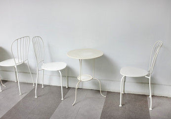 White chairs and table against white wall background.