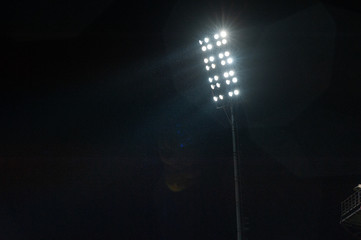 Stadium light against night sky. High mast of spot light. Light lines