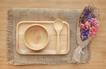 Set of wooden tray, bowl and spoon on sack against wood board background