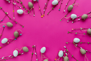 Easter decor. The branches of willow and decorative eggs are laid out on a pink background