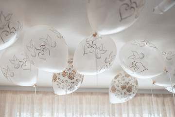 white balloons with a pattern in the form of pigeons and hearts on the ceiling of the room