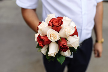Obraz na płótnie Canvas Bridal bouquet of red and white roses in the groom's hand