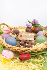 Panier de Pâques avec oeufs en chocolat, tulipes et texte Happy Easter