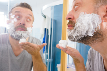 Guy shaving his beard in bathroom