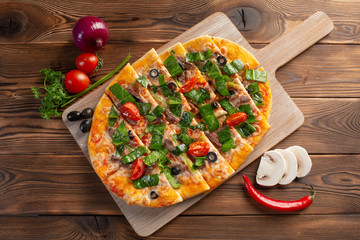 pizza with veal and dried tomatoes on a wooden background
