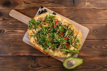 pizza with seafood and arugula on a wooden background