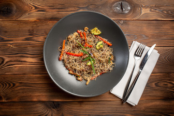 seafood noodle chow in black plate on wooden background