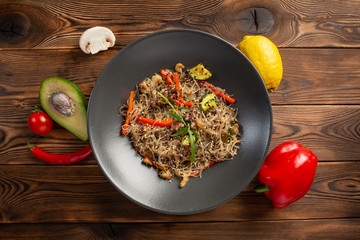 seafood noodle chow in black plate on wooden background
