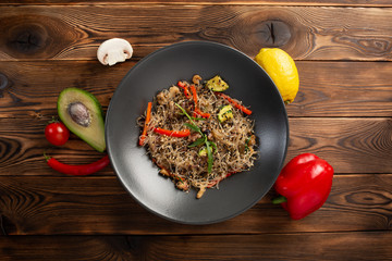 seafood noodle chow in black plate on wooden background
