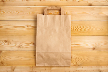 Paper bag on a natural wooden texture. Disposable paper bag on wooden background
