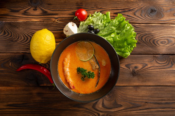 soup tom yam in a black plate on a wooden background