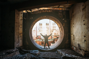 Man traveller and explorer inside round door or gate to abandoned nuclear rector or generator room in ruined and destroyed Crimean Nuclear Power Plant