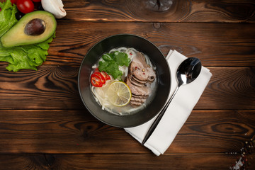 Japanese pho bo soup in a black plate on wooden background