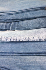 Naklejka premium stack of various shades of blue jeans as background