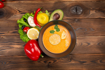 tom kha soup with lemon and vegetables on a wooden background