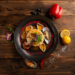 baked squid rings with rice and vegetables on a wooden background