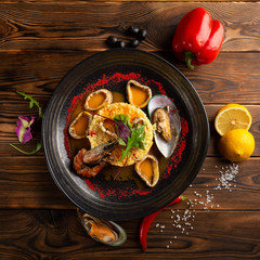 baked squid rings with rice and vegetables on a wooden background