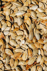 Fried pumpkin seeds lying on the old rustic background. Vegetarian superfood. Healthy diet. Natural texture background. Vertical photo.