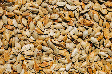 Fried pumpkin seeds lying on the old rustic background. Vegetarian superfood. Healthy diet. Natural texture background. Vertical photo.