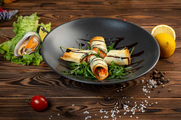 crispy spring rolls with salmon in a black plate on wooden background