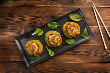 marine cutlets with mashed green peas in a black plate on a wooden background