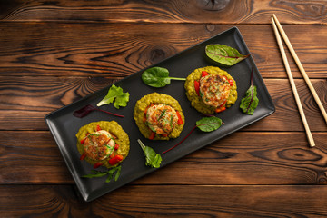 marine cutlets with mashed green peas in a black plate on a wooden background