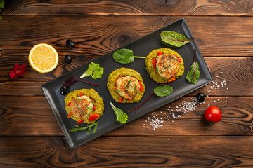 marine cutlets with mashed green peas in a black plate on a wooden background