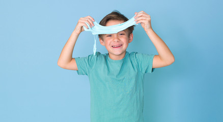 cool, pretty boy plays with homemade slime in front of a blue background and is having a lot of fun