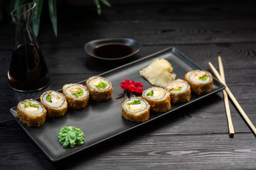 Fototapeta na wymiar a set of rolls with cheese and herbs on a rectangular black plate on a black wooden background