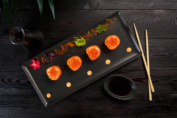 Sushi rolls set with tuna on a black rectangular plate on a black wooden background