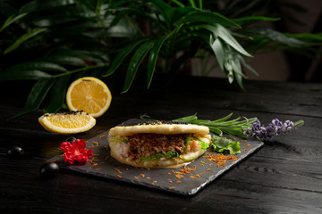 bao with lamb on a black plate on a wooden background