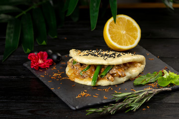 bao with lamb on a black plate on a wooden background