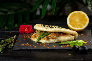 bao with lamb on a black plate on a wooden background