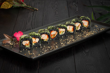 set of black rolls on a black rectangular plate on a dark wooden background