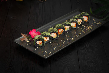 set of black rolls on a black rectangular plate on a dark wooden background